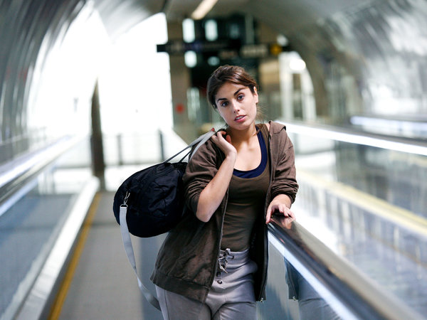 Femme avec un sac sur un trottoir roulant